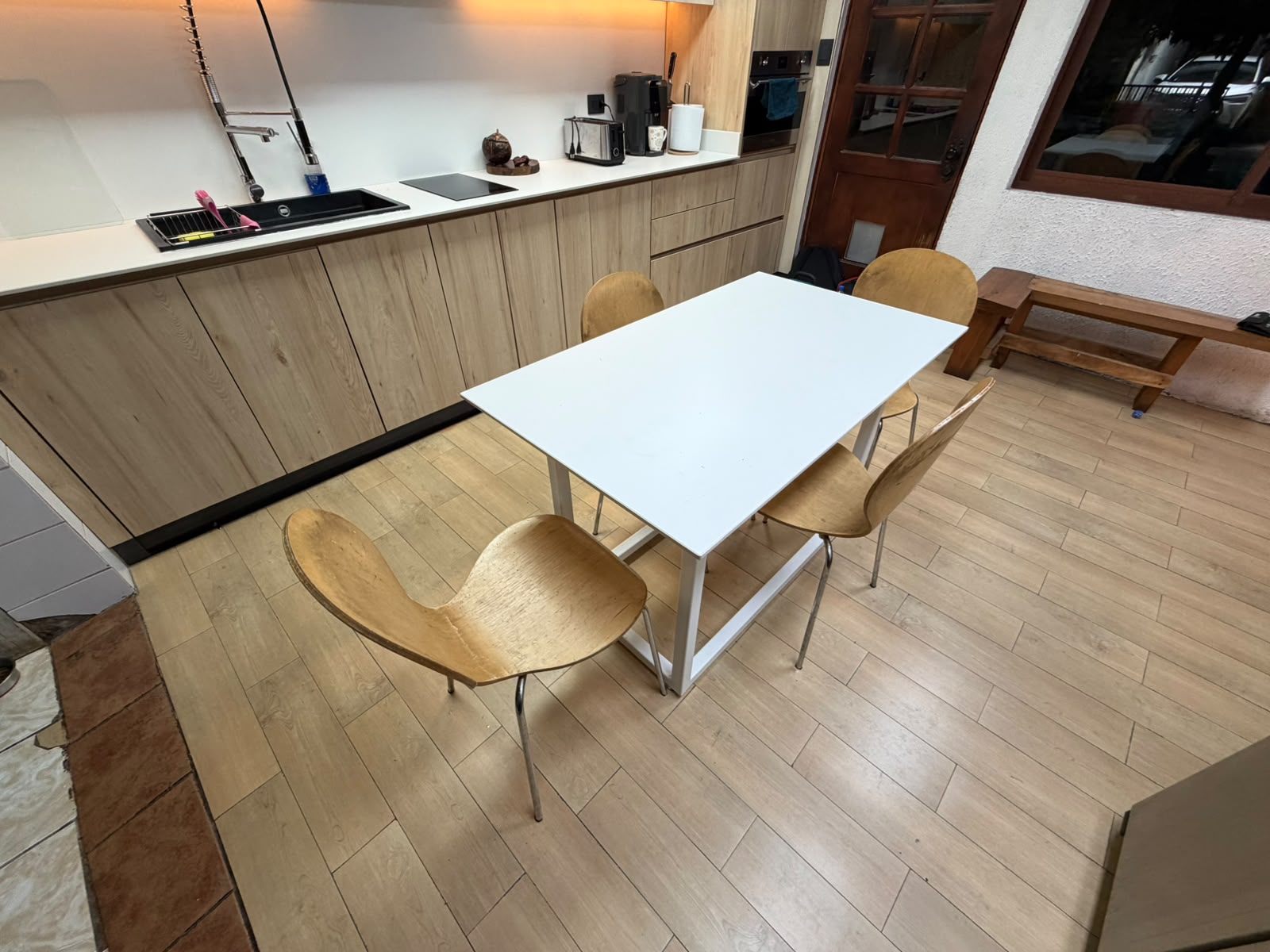Cocina y comedor integrados con sillas de madera y luz cálida