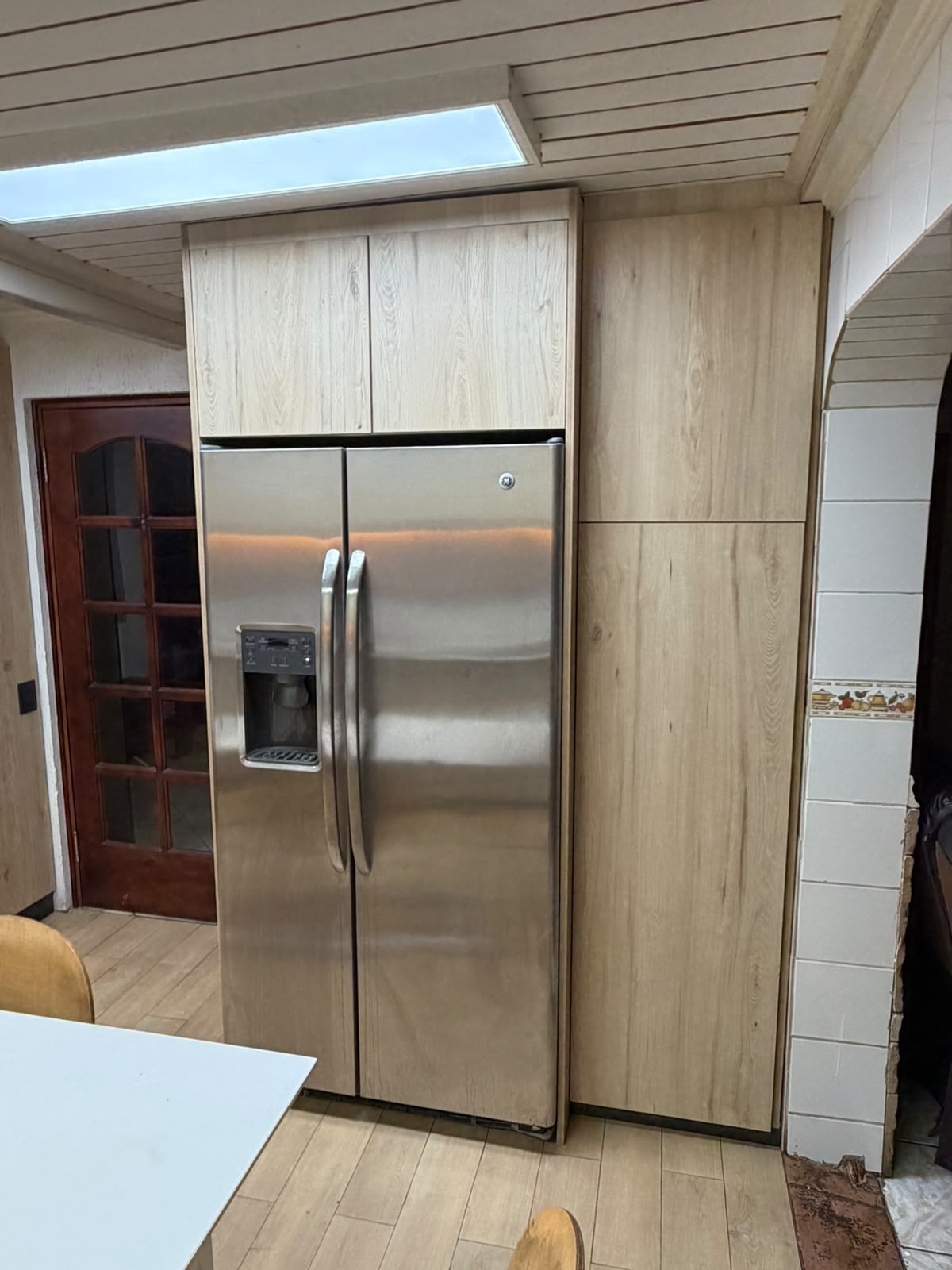 Refrigerador integrado en mueble de madera clara hasta el techo